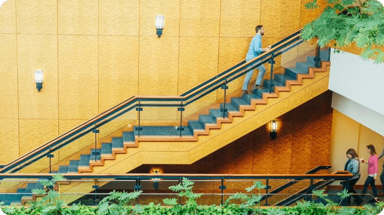Zoomed out shot of people going up and down a vibrant yellow staircase.
