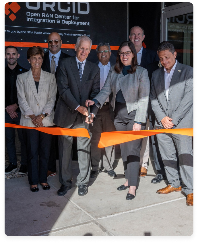A group of people in business attire participating in a ribbon-cutting ceremony at the ORCID Center.